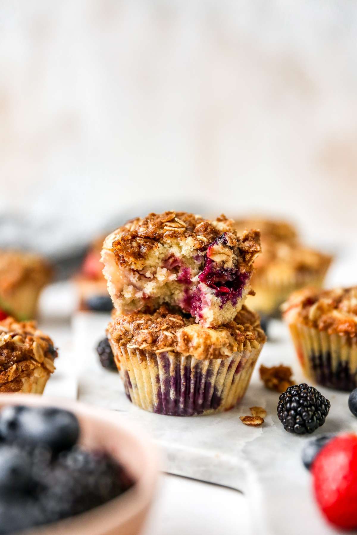 Two muffins stacked, one with a bite out of it.