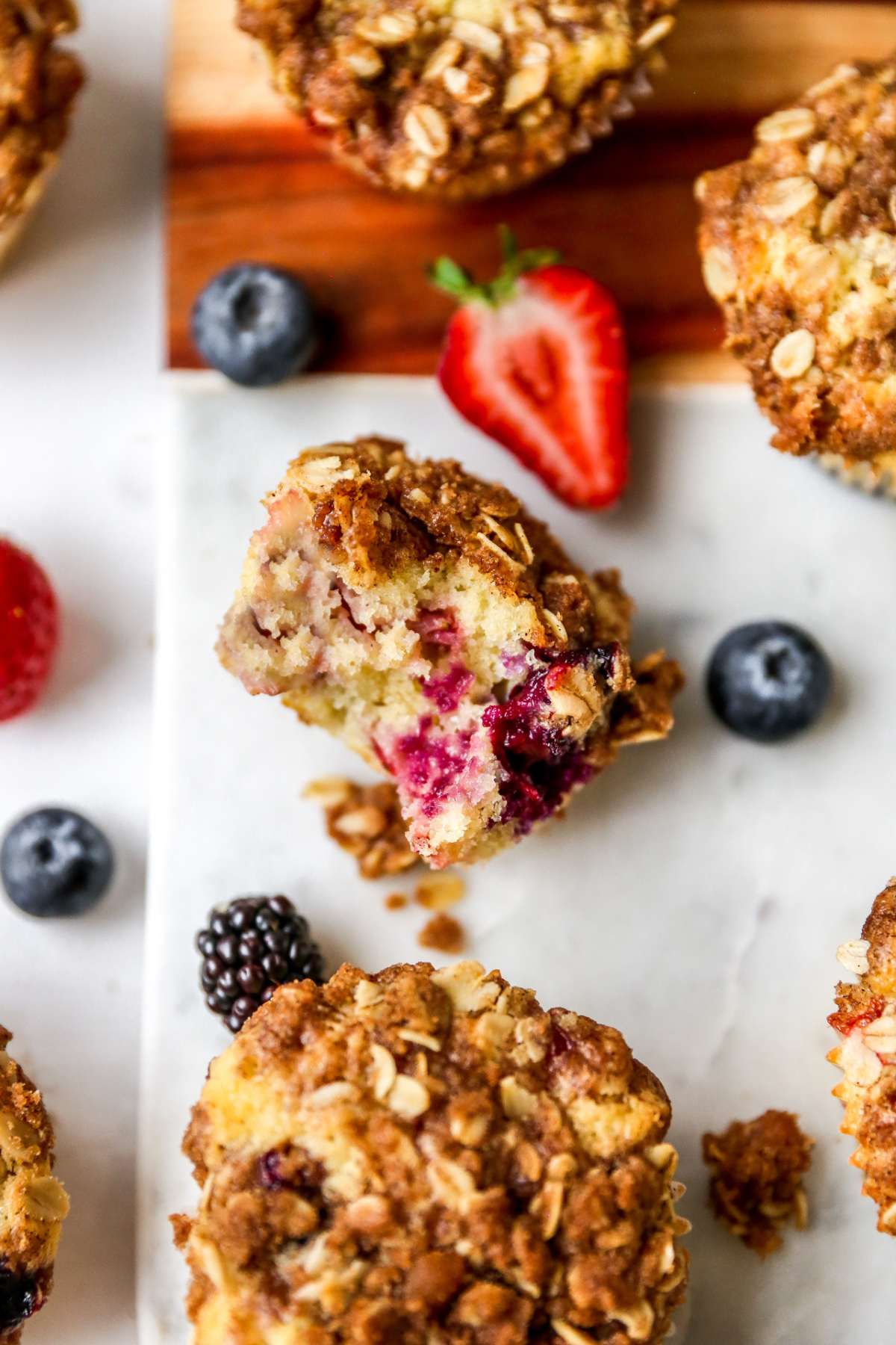 Mixed berry muffin with a bite taken out next to other muffins.