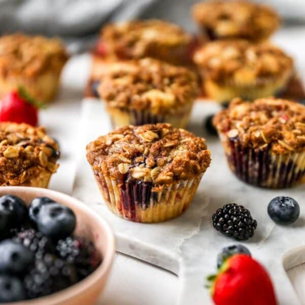 Mixed berry muffins near fresh blueberries and strawberries.