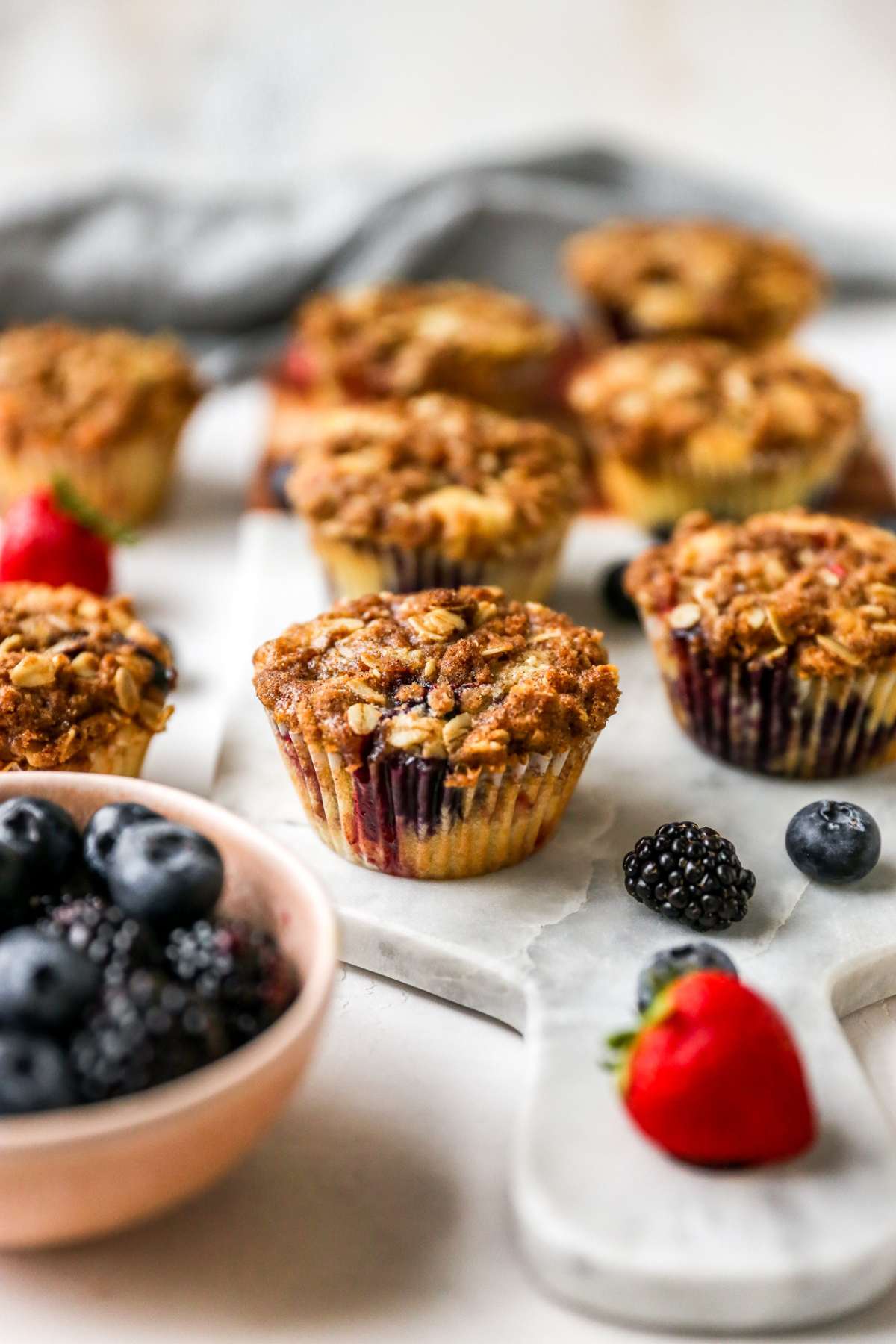 Mixed berry muffins near fresh blueberries and strawberries.