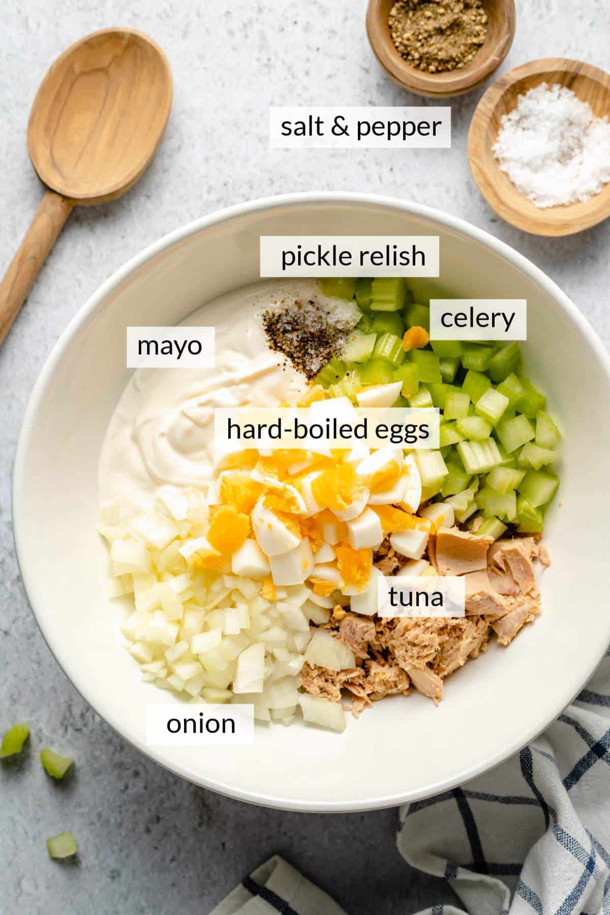 Adding boiled egg with tuna, chopped onion and celery into a large bowl.