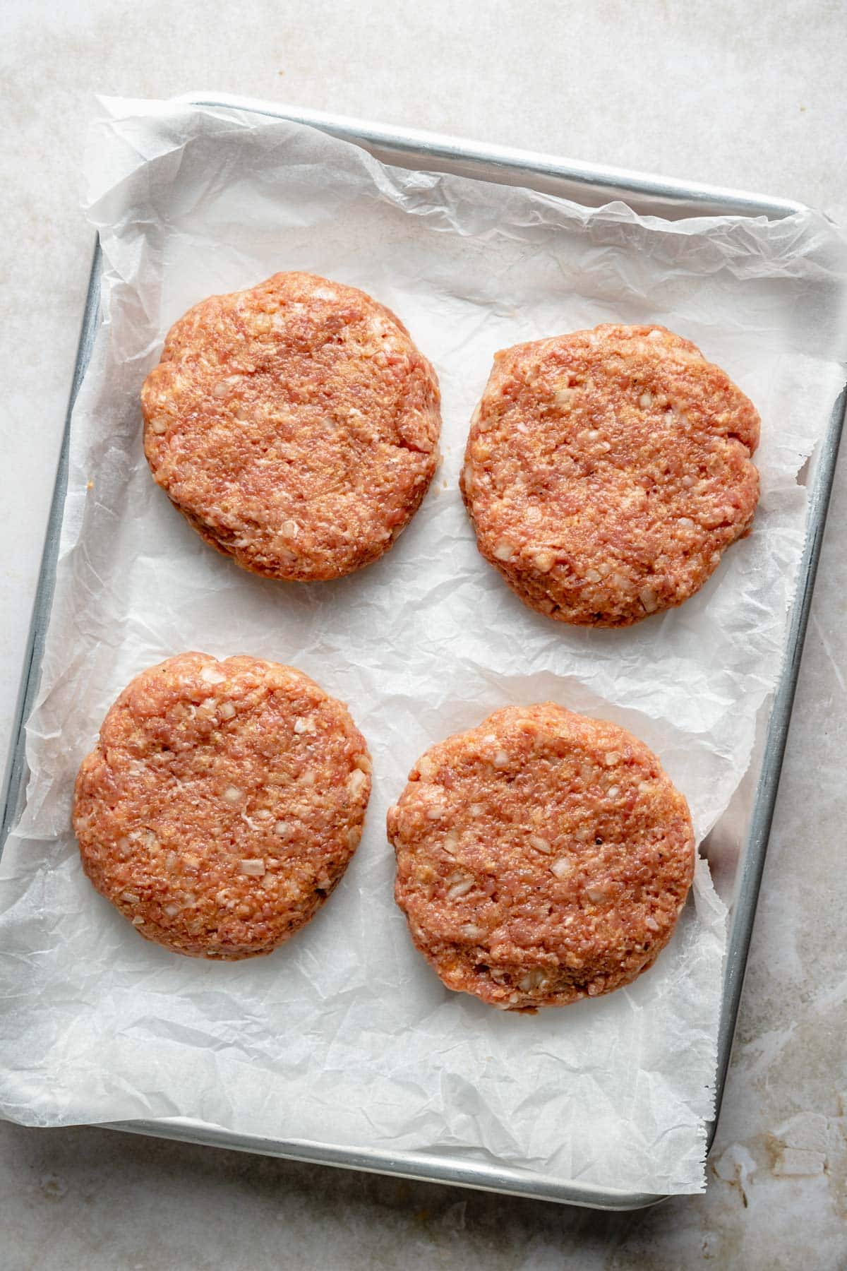 Ground chicken patties on a baking pan.