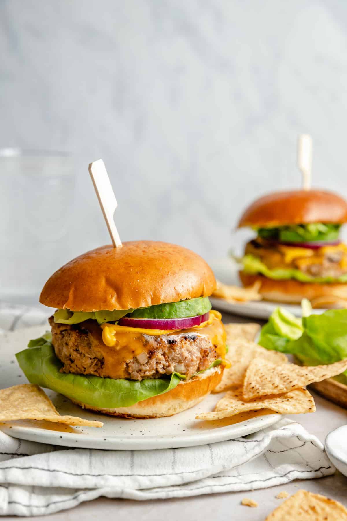 Chicken burgers topped with avocado, onion and cheese.