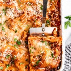 Using a spatula to scoop out a serving of lasagna.