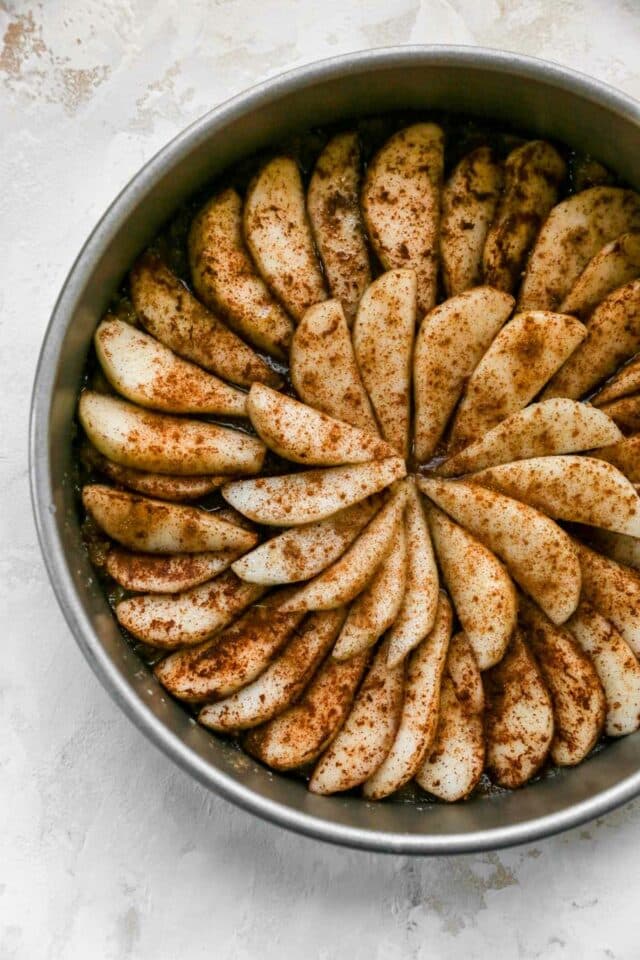 Pear slices arranged in a round cake pan.