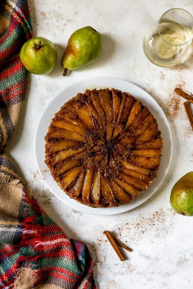 Upside down pear cake near a glass of wine and pears.