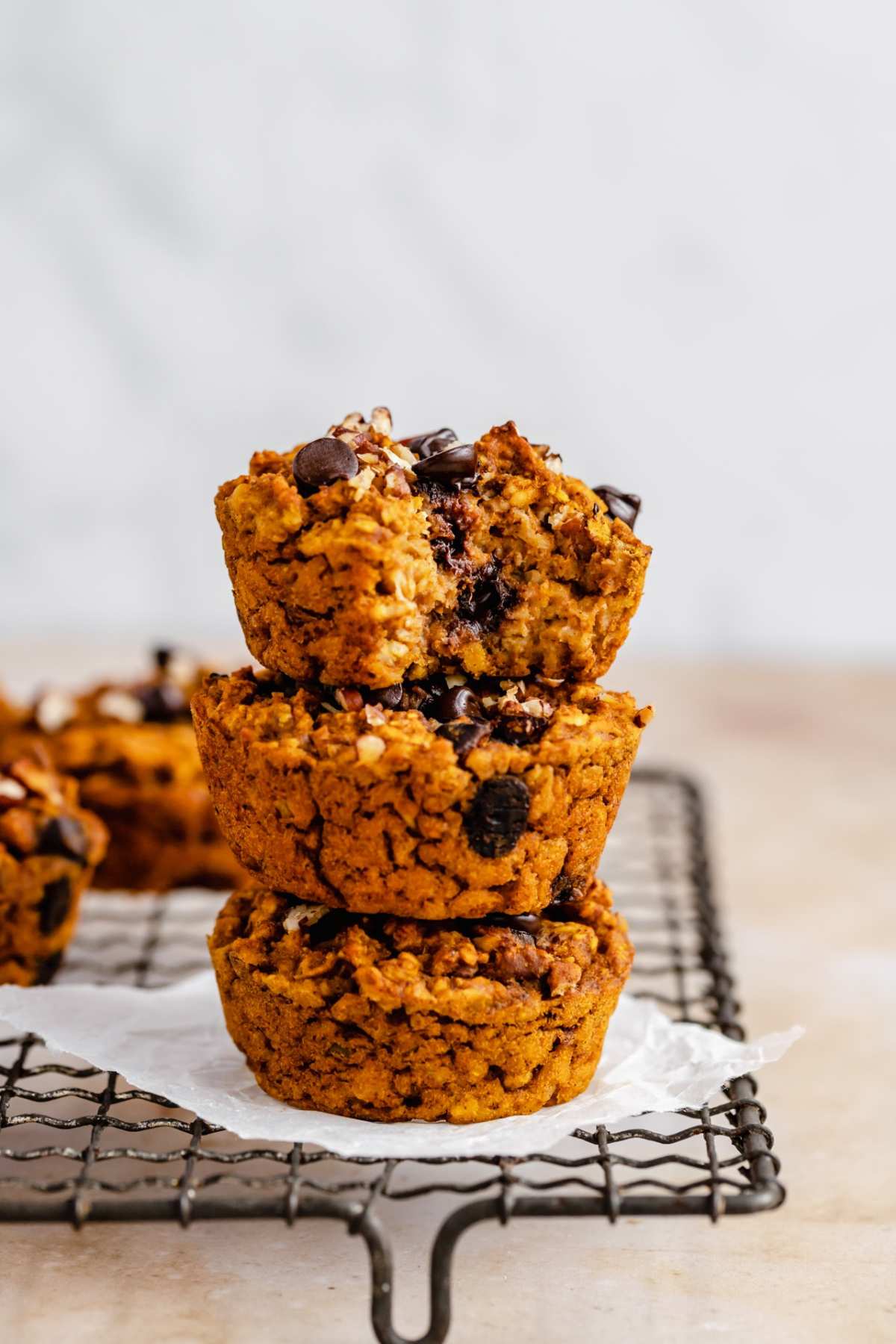 Pumpkin oatmeal muffins stacked on a wire rack.