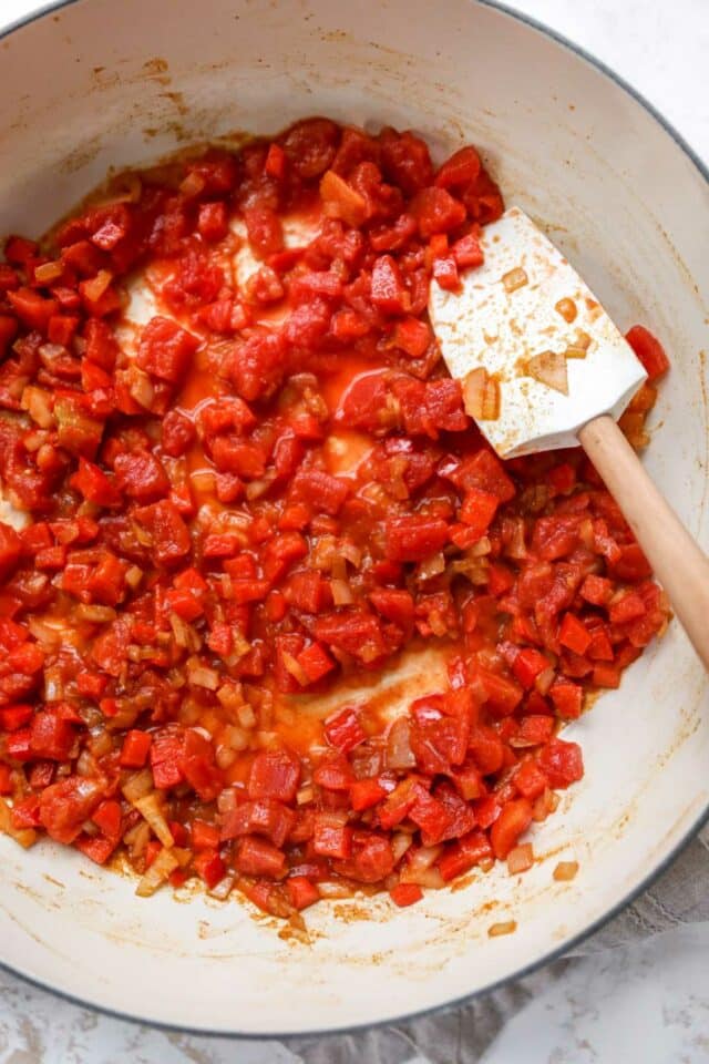 Cooking tomatoes and red bell pepper in a large skillet.