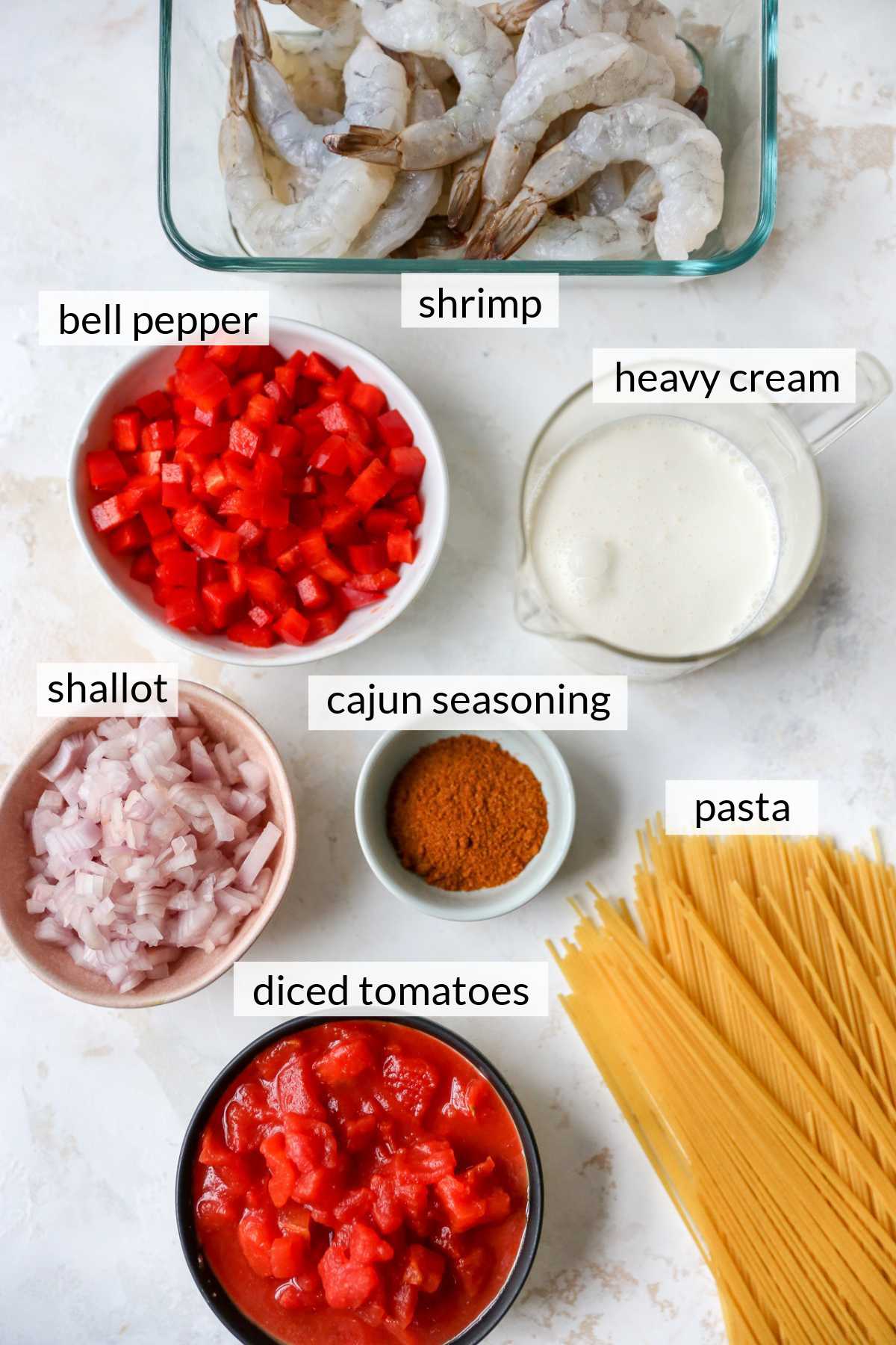 Shrimp, pasta, tomatoes, bell pepper, heavy cream, and spices divided into small bowls.