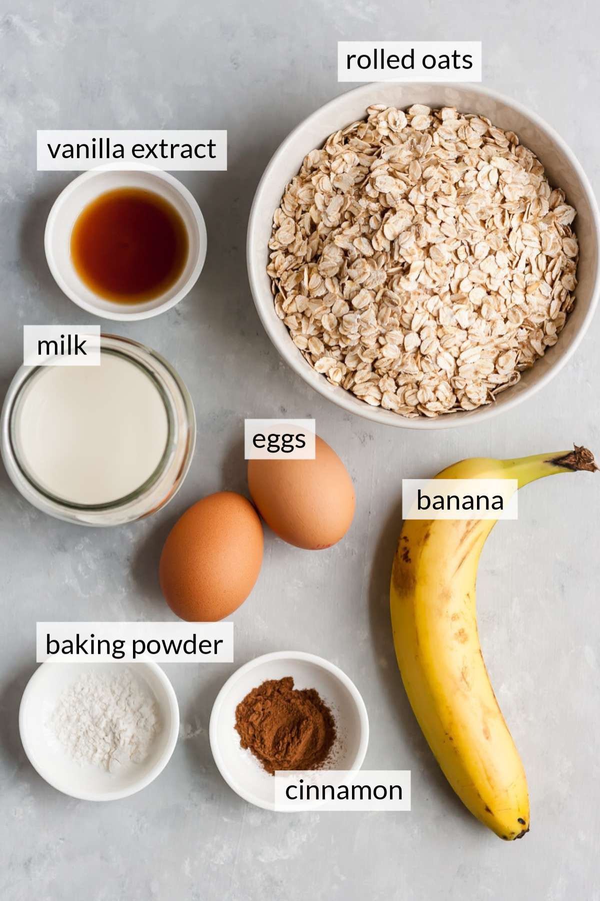 Bowl filled with oats, milk, cinnamon and vanilla near eggs and a banana.