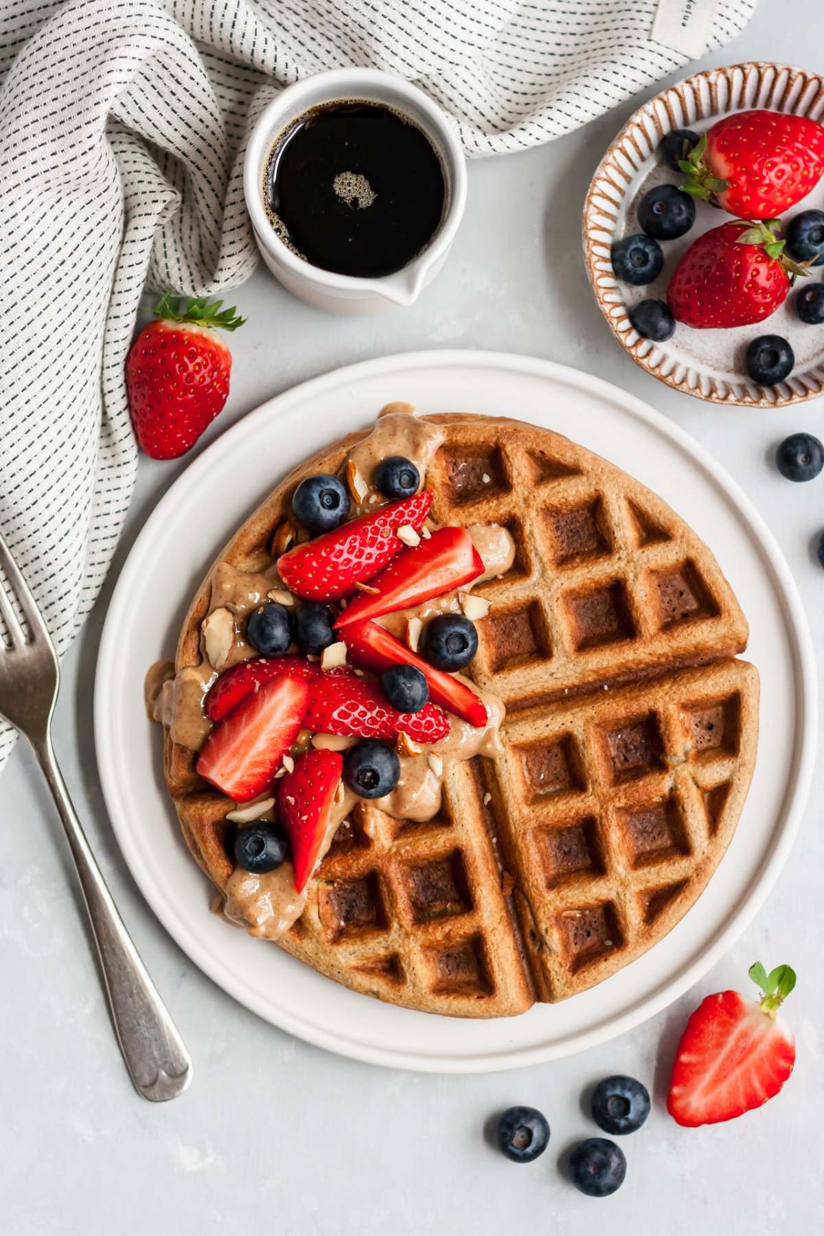 Banana oat waffle topped with berries and almond butter.