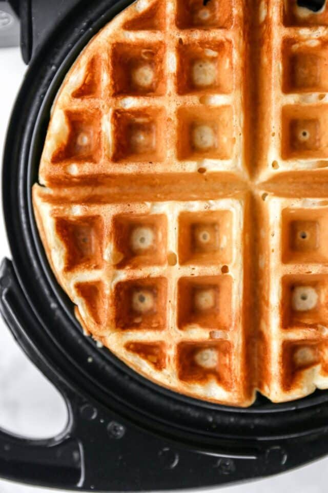 Waffle cooking on a waffle iron.