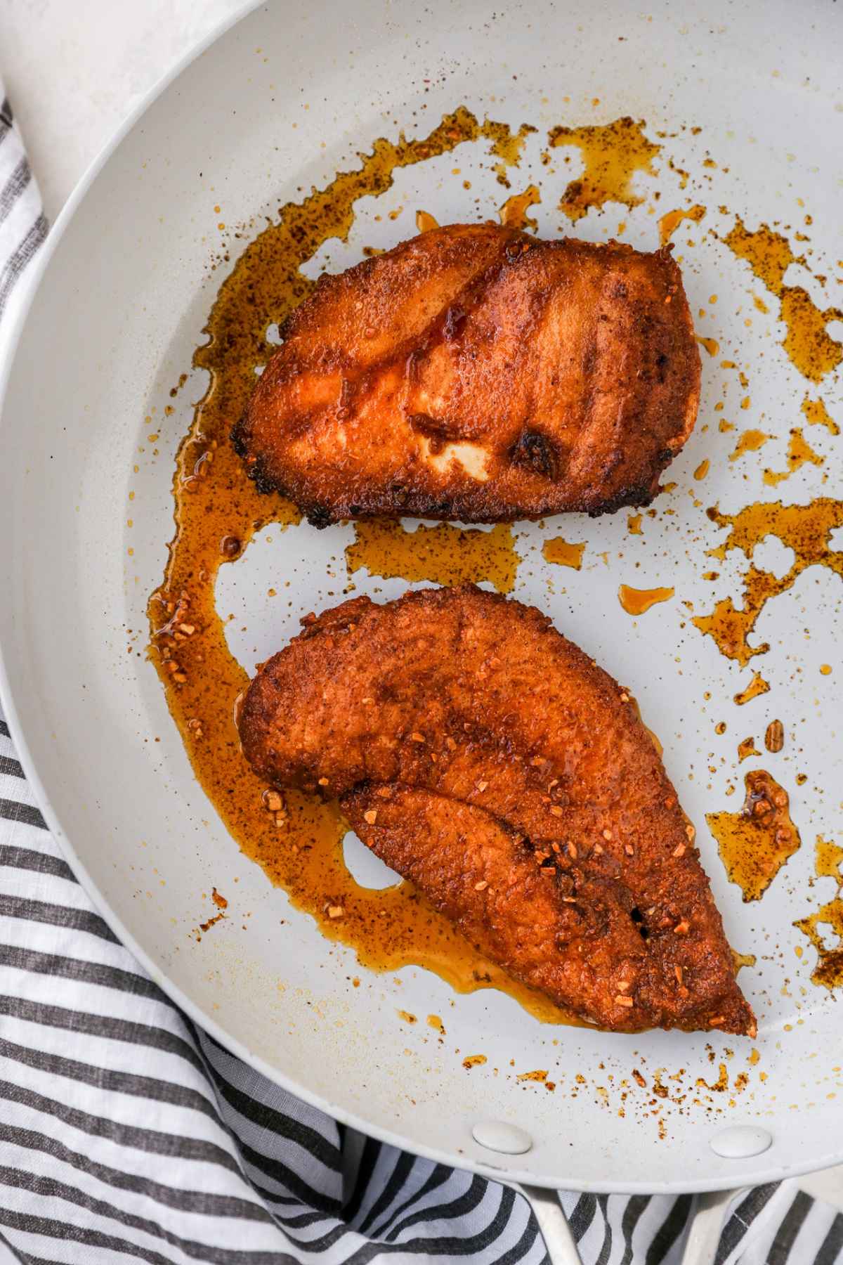 Seasoned chicken cooking in a skillet.