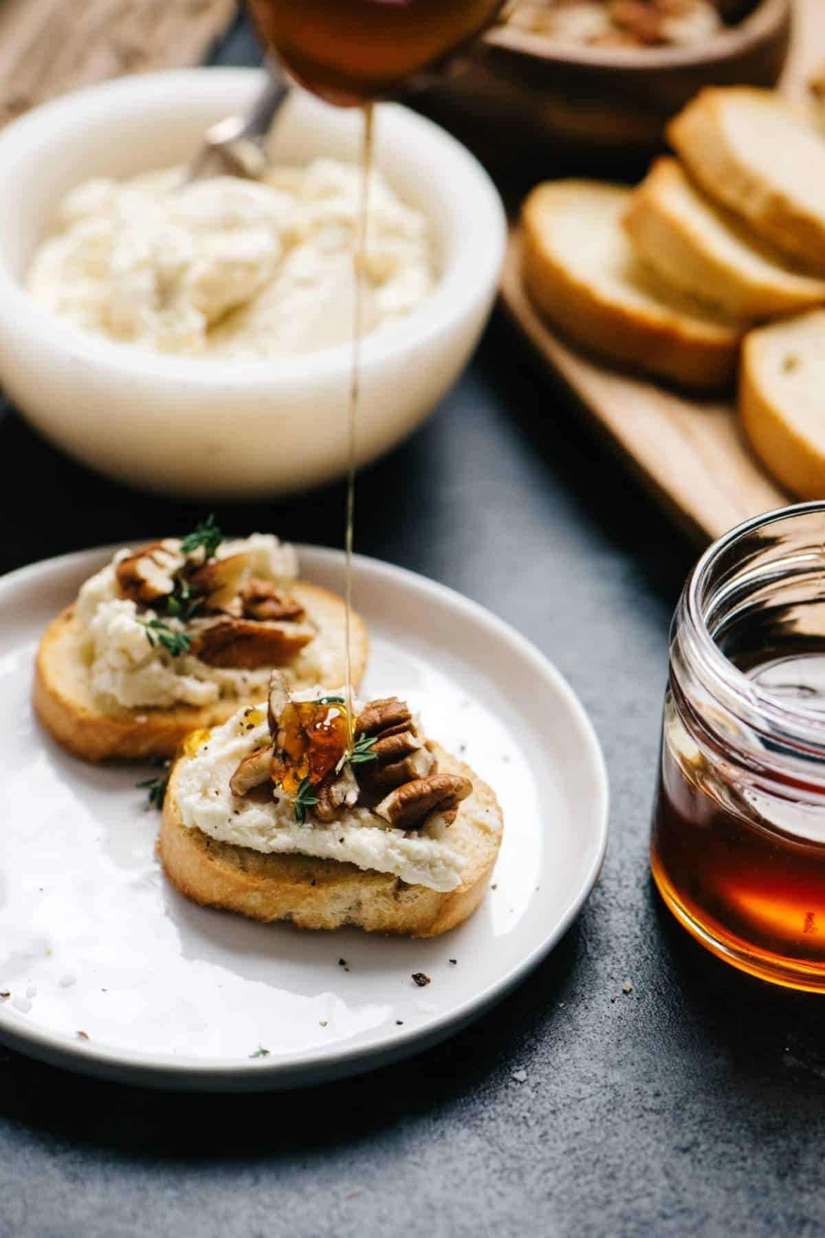 Drizzling honey over pecans and goat cheese on a crostini.