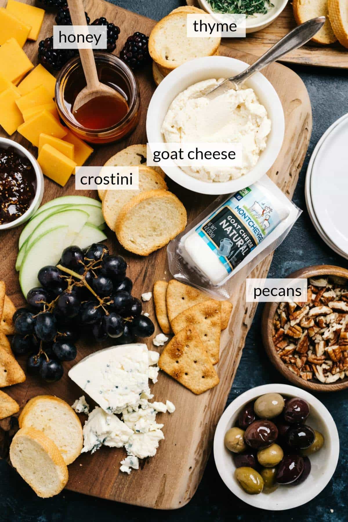 Crostini, goat cheese, fruit and other cheeses on a cheese board.