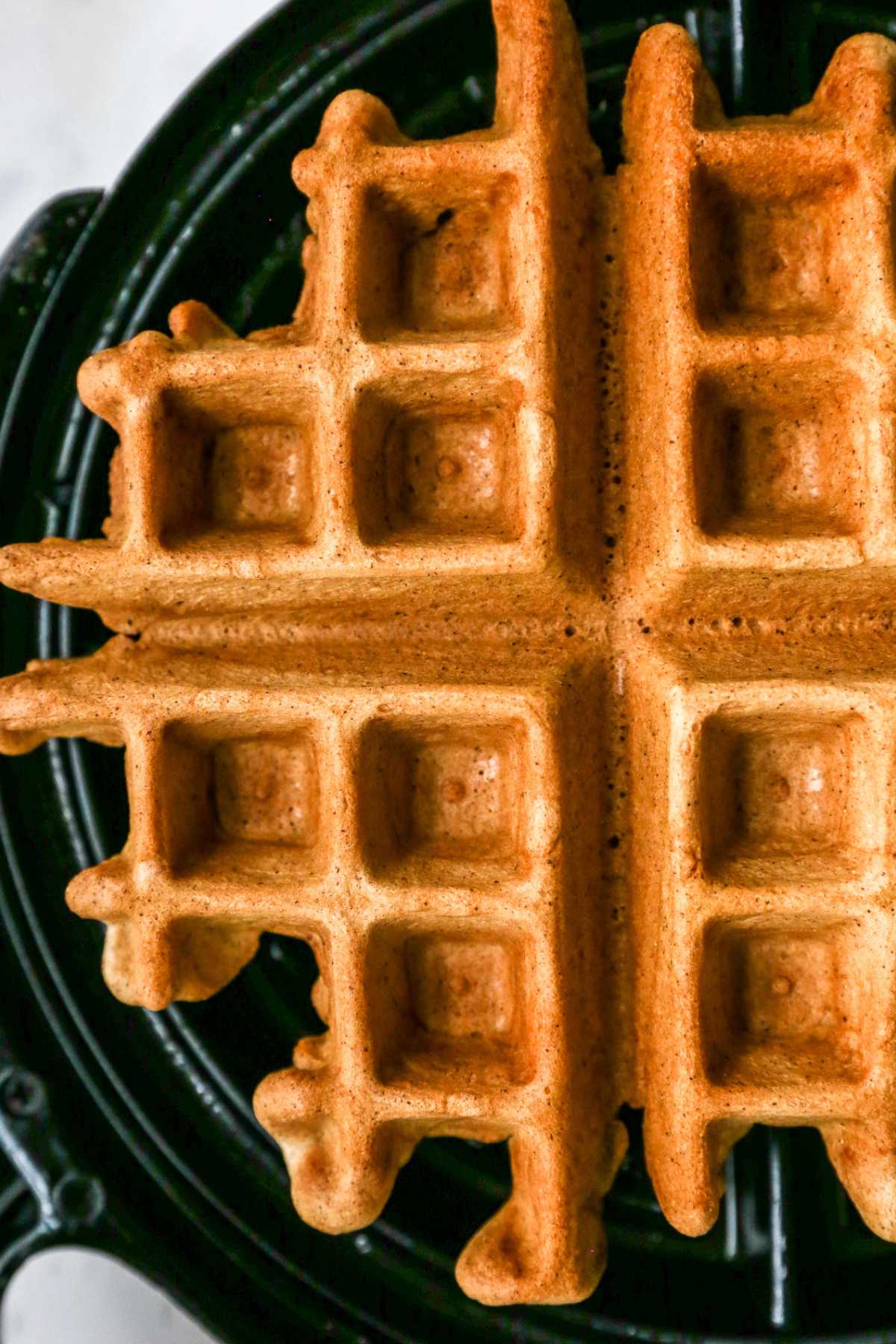 Waffle cooking on a waffle iron.