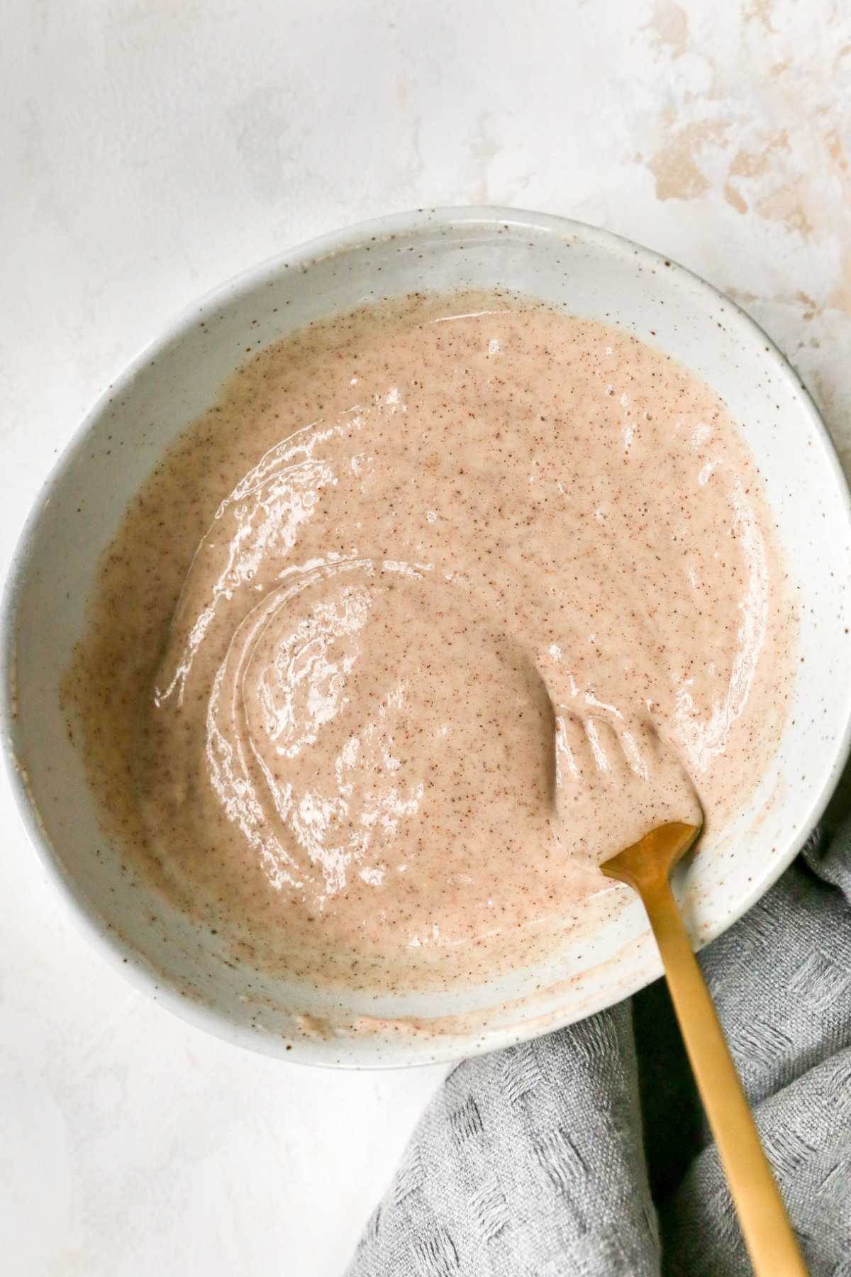 Stirring batter with a fork in a white bowl.