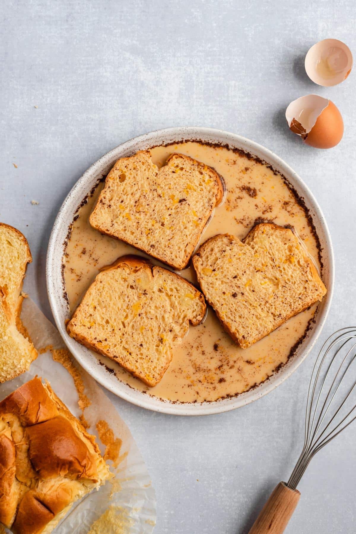 Dipping bread into egg custard mixture in shallow bowl.