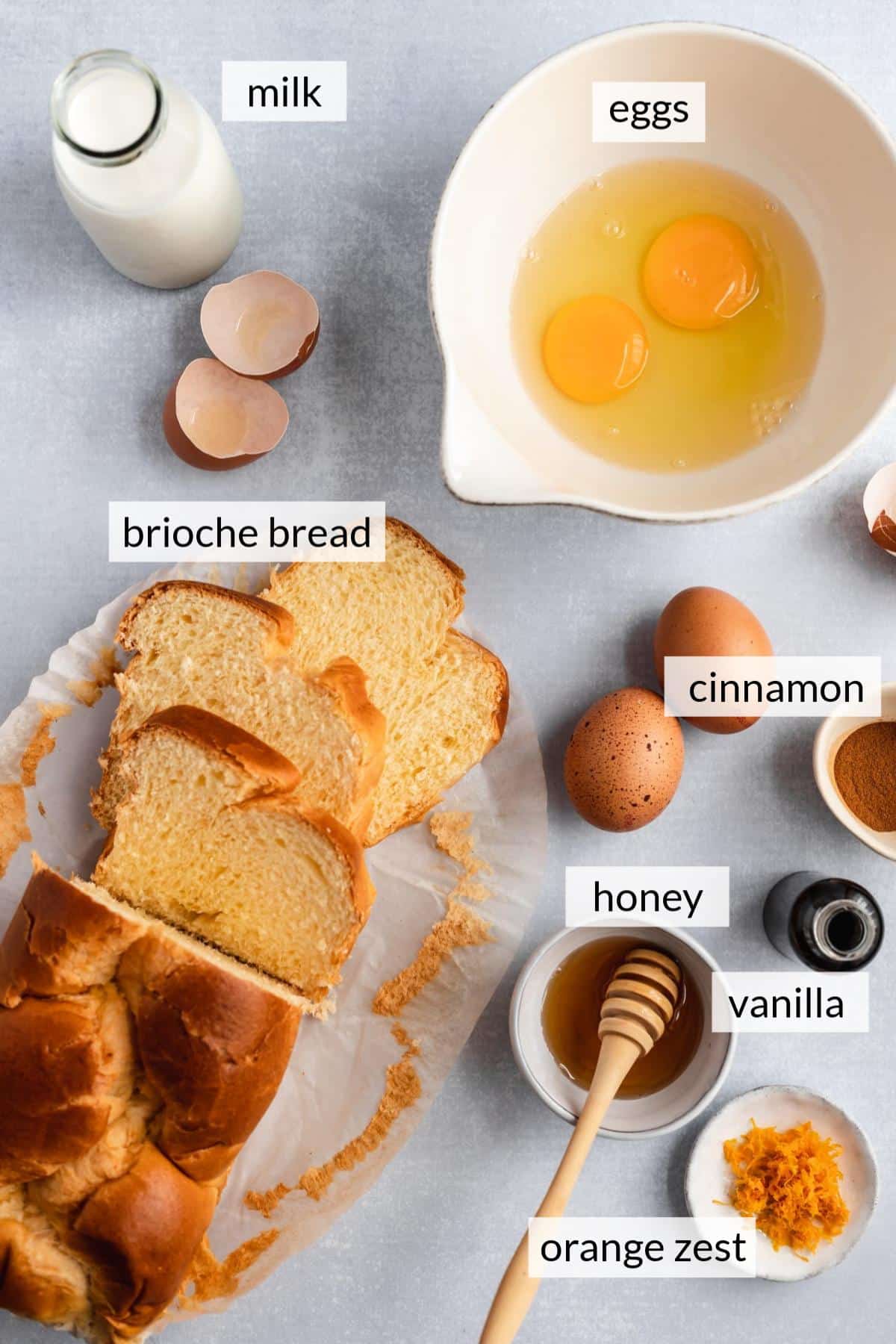 Sliced bread near bowls of eggs, cinnamon, maple syrup and orange zest.