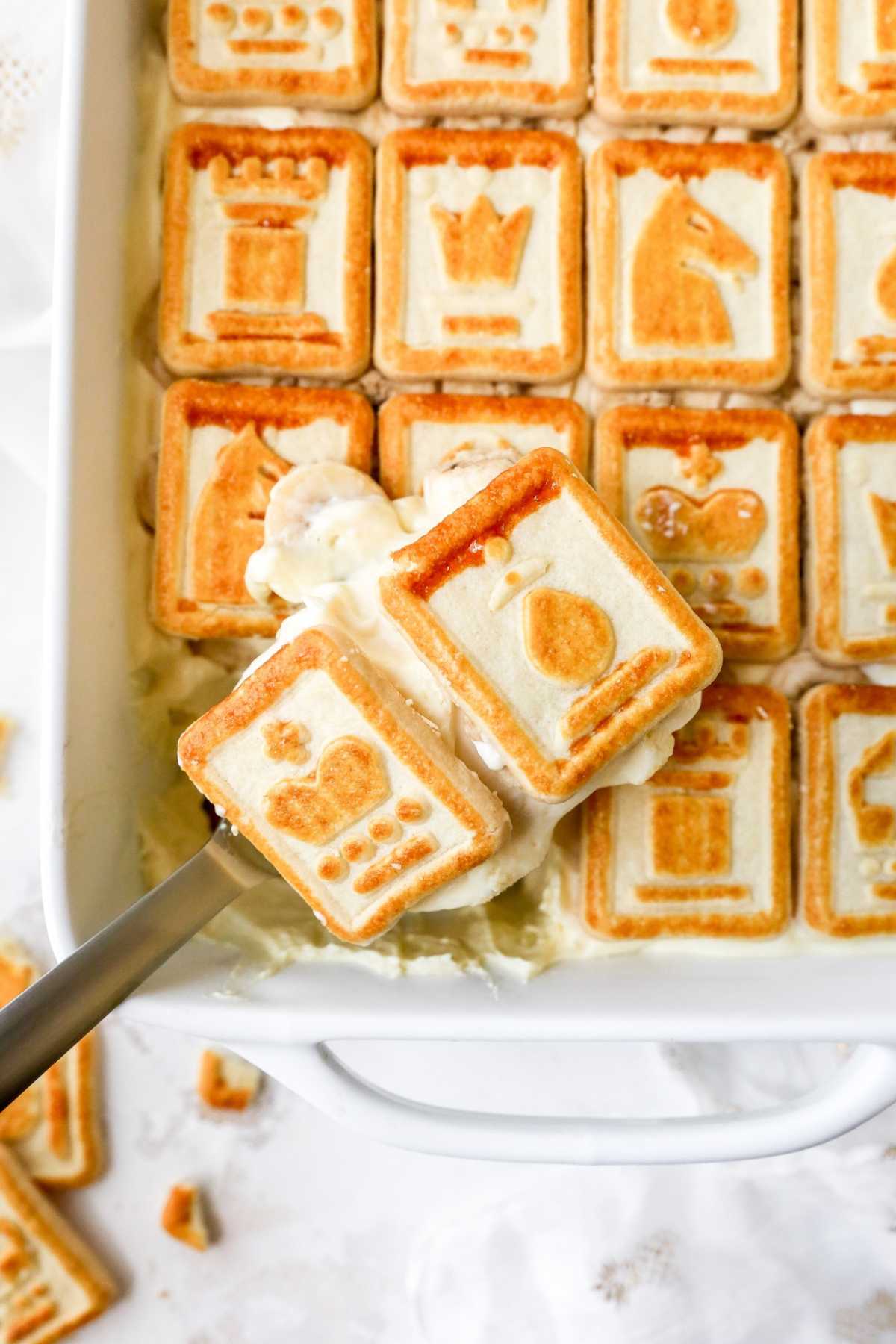 Serving banana pudding out of a dish with a large serving spoon.