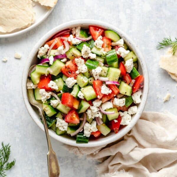 Cucumber tomato salad served with a serving spoon.