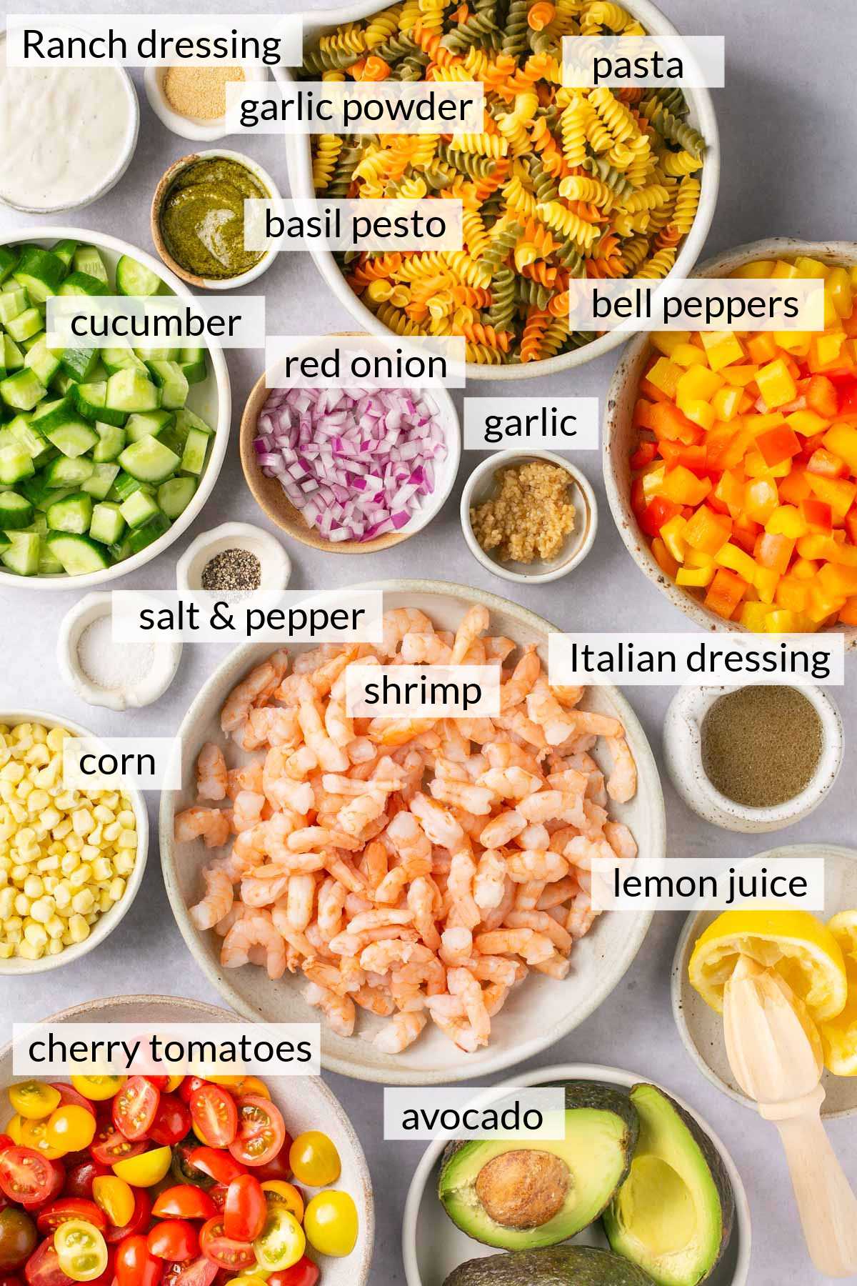 Shrimp, cucumber, onions, corn, bell pepper, garlic and uncooked pasta divided into small bowls.