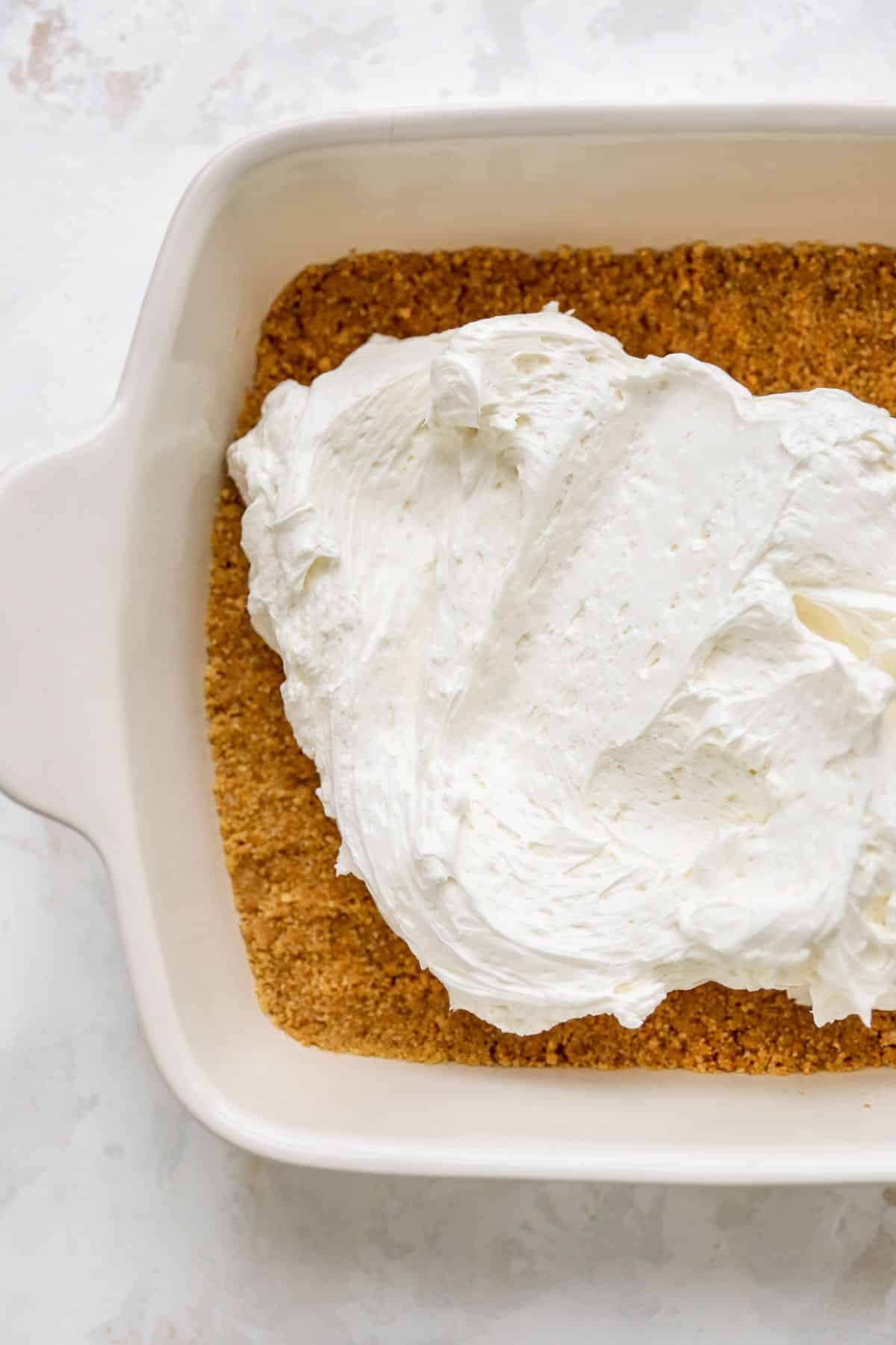 Spreading cream cheese filling over graham cracker crust.