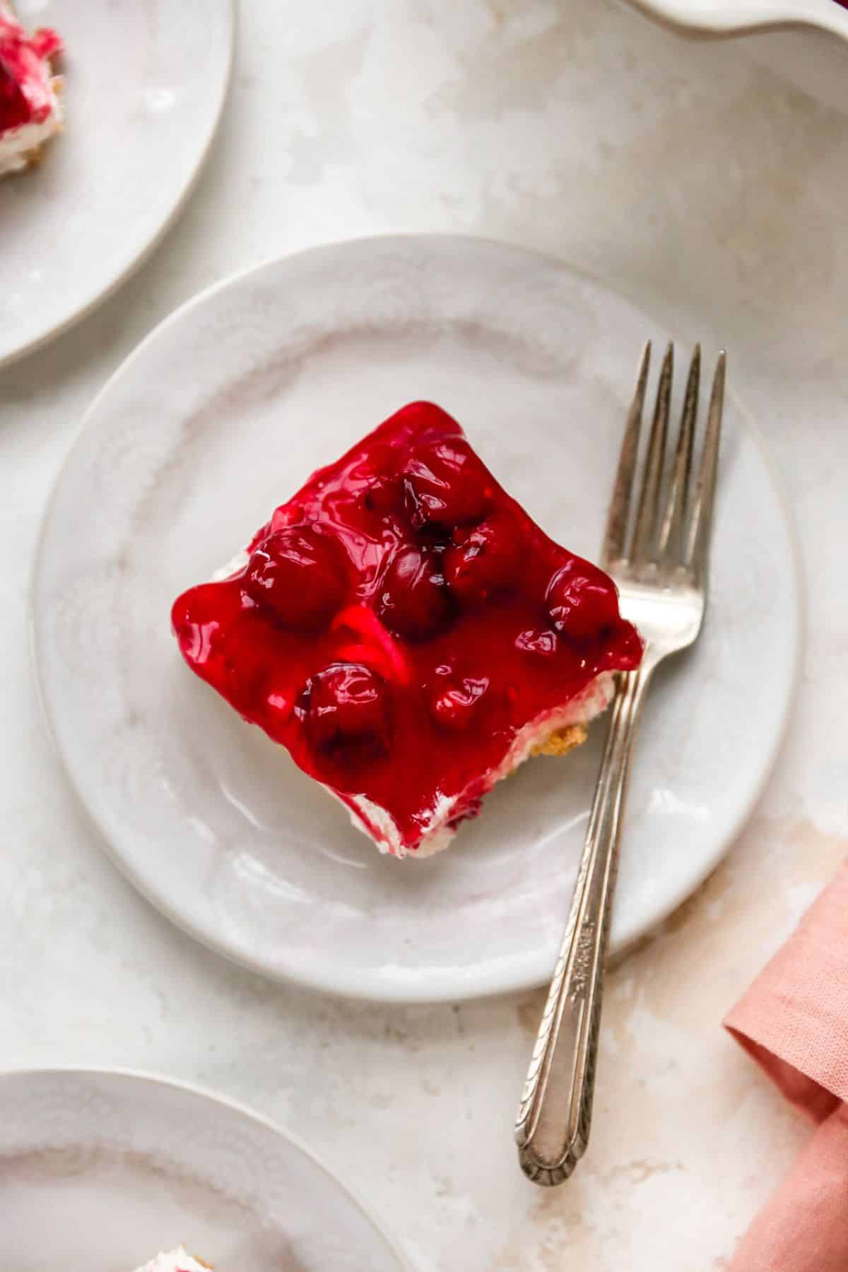 Slice of cherry dessert on a white plate.