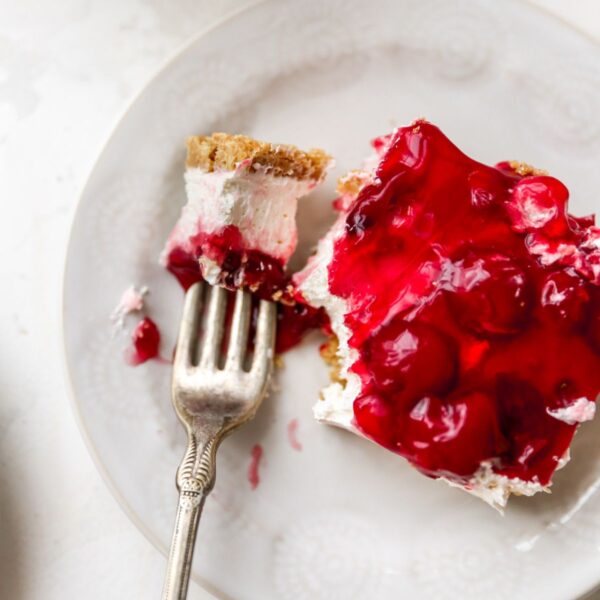 Slice of cherry delight dessert on a white plate.