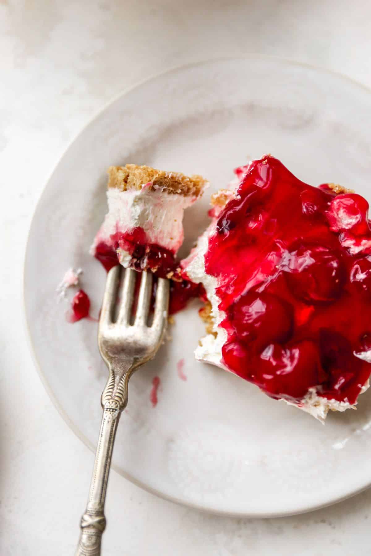 Slice of cherry delight dessert on a white plate.