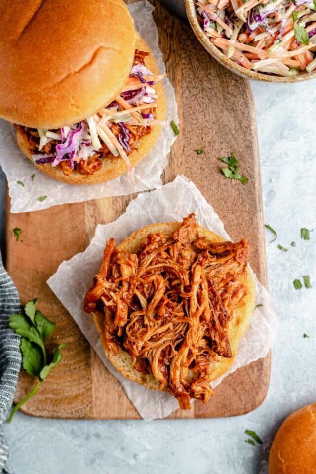 Topping a bun with slow cooker pulled chicken.