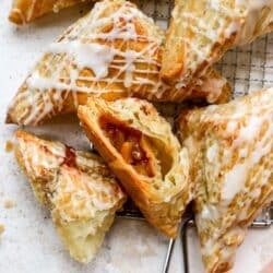 Apple turnovers drizzled with icing with one cut open.