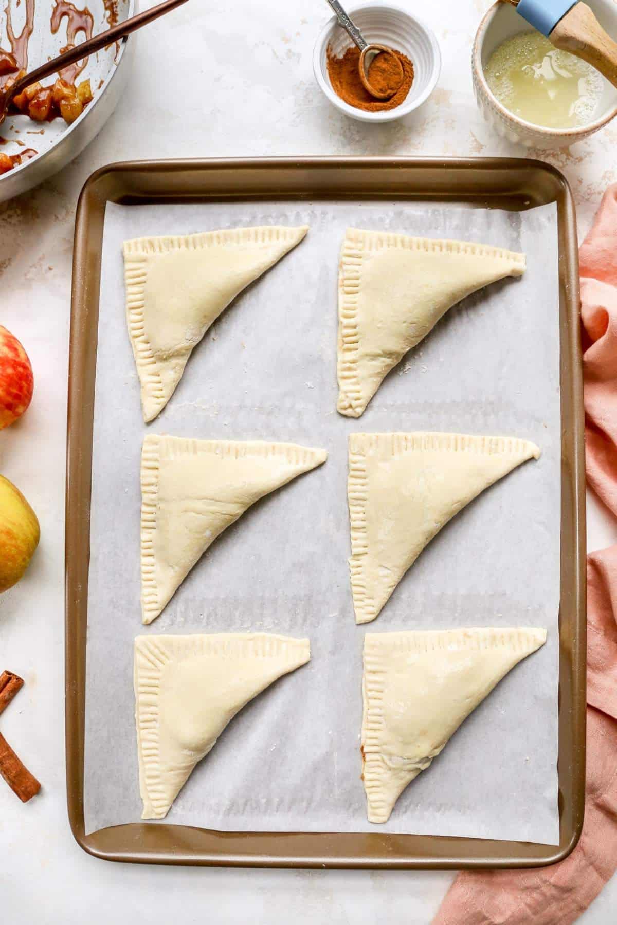 Puff pastry folded over on a parchment paper lined cookie sheet.