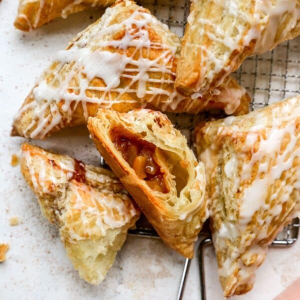 Apple turnovers drizzled with icing with one cut open.