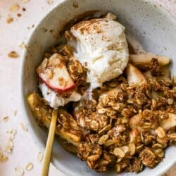 Spoonful of healthy apple crisp and vanilla ice cream in a bowl.