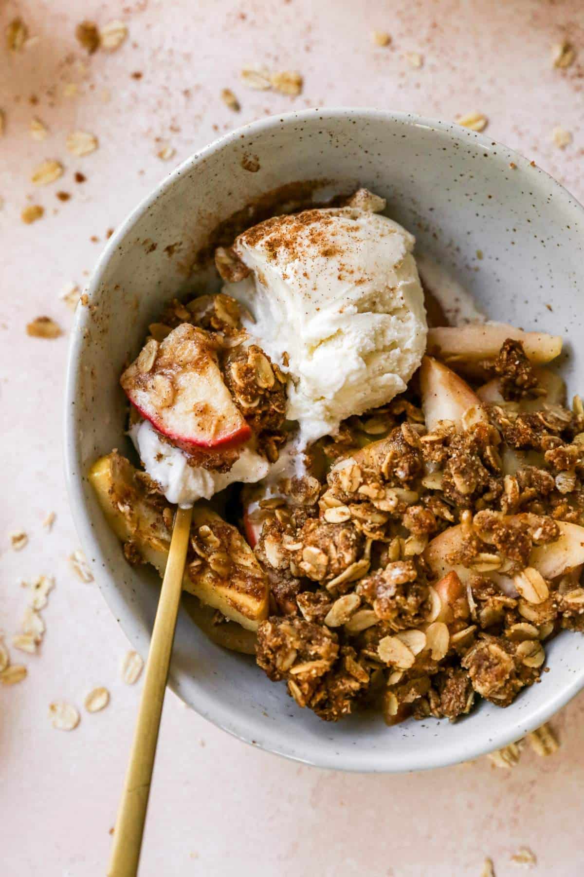 Spoonful of healthy apple crisp and vanilla ice cream in a bowl.