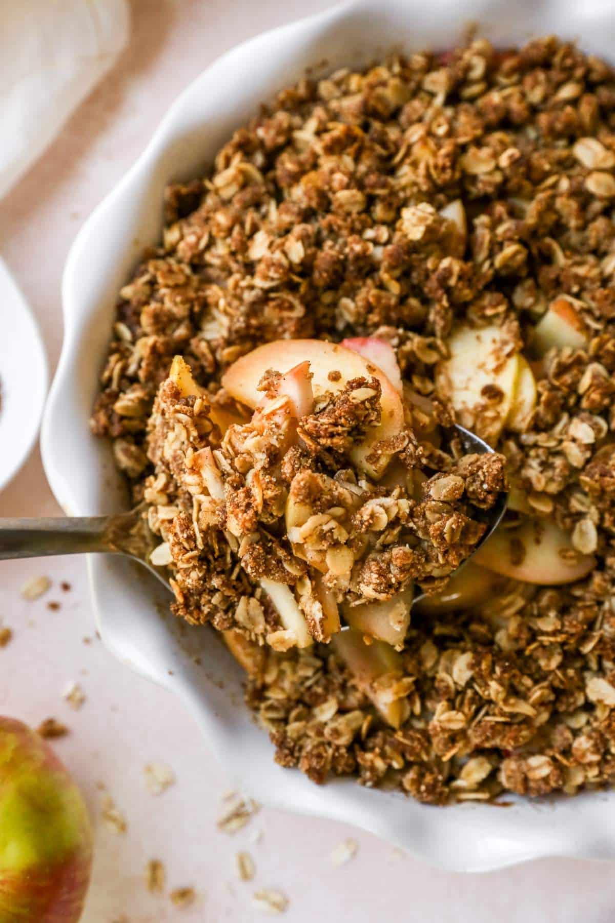 Serving a apple crisp out of a white pie plate.