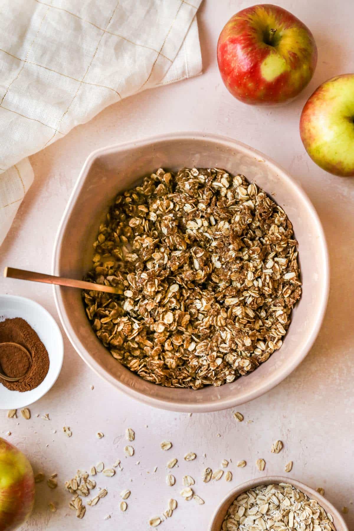 Oat mixture in a large bowl near a small bowl of cinnamon.