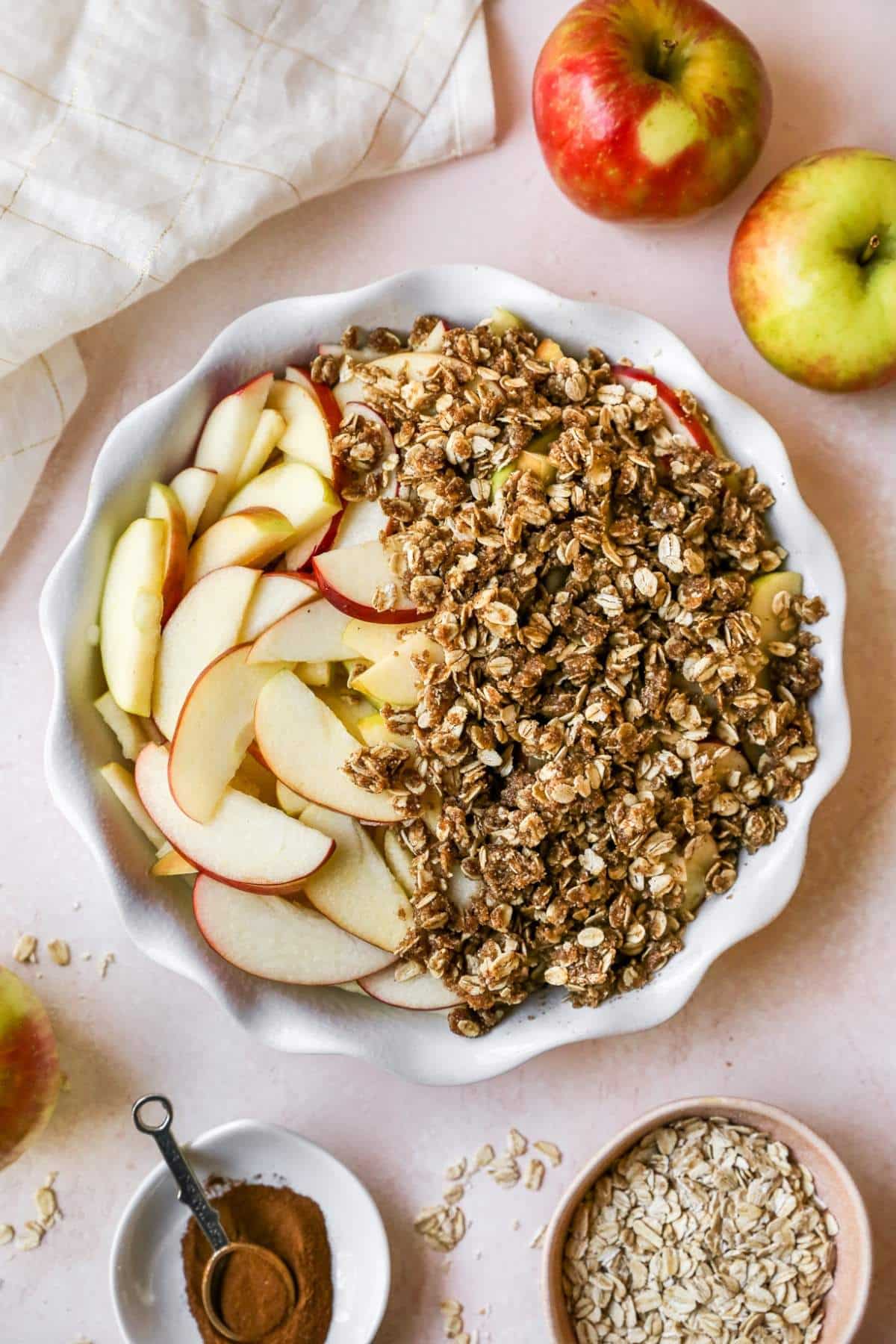 Covering apple slices with oat mixture in a pie dish.