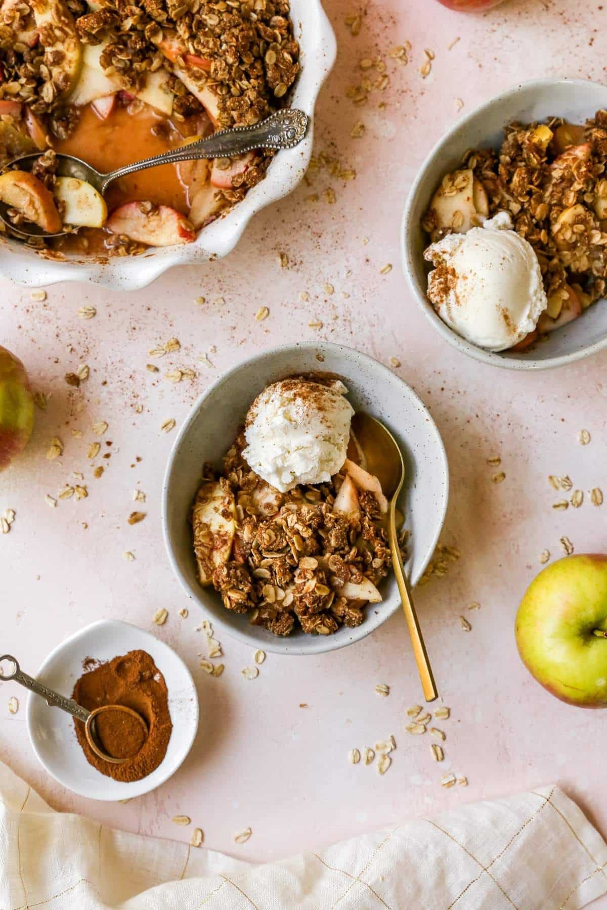 Apple crisp served in small bowls with vanilla ice cream.