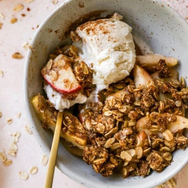 Spoonful of healthy apple crisp and vanilla ice cream in a bowl.