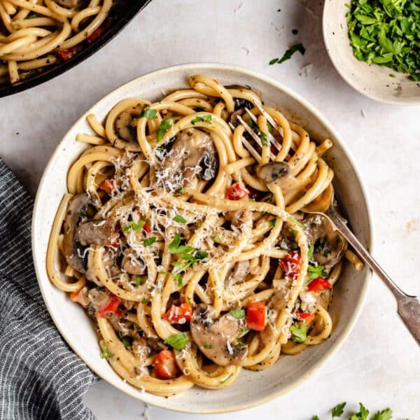 Pasta with a mushroom sauce in a white bowl with the pasta swirled around the fork.