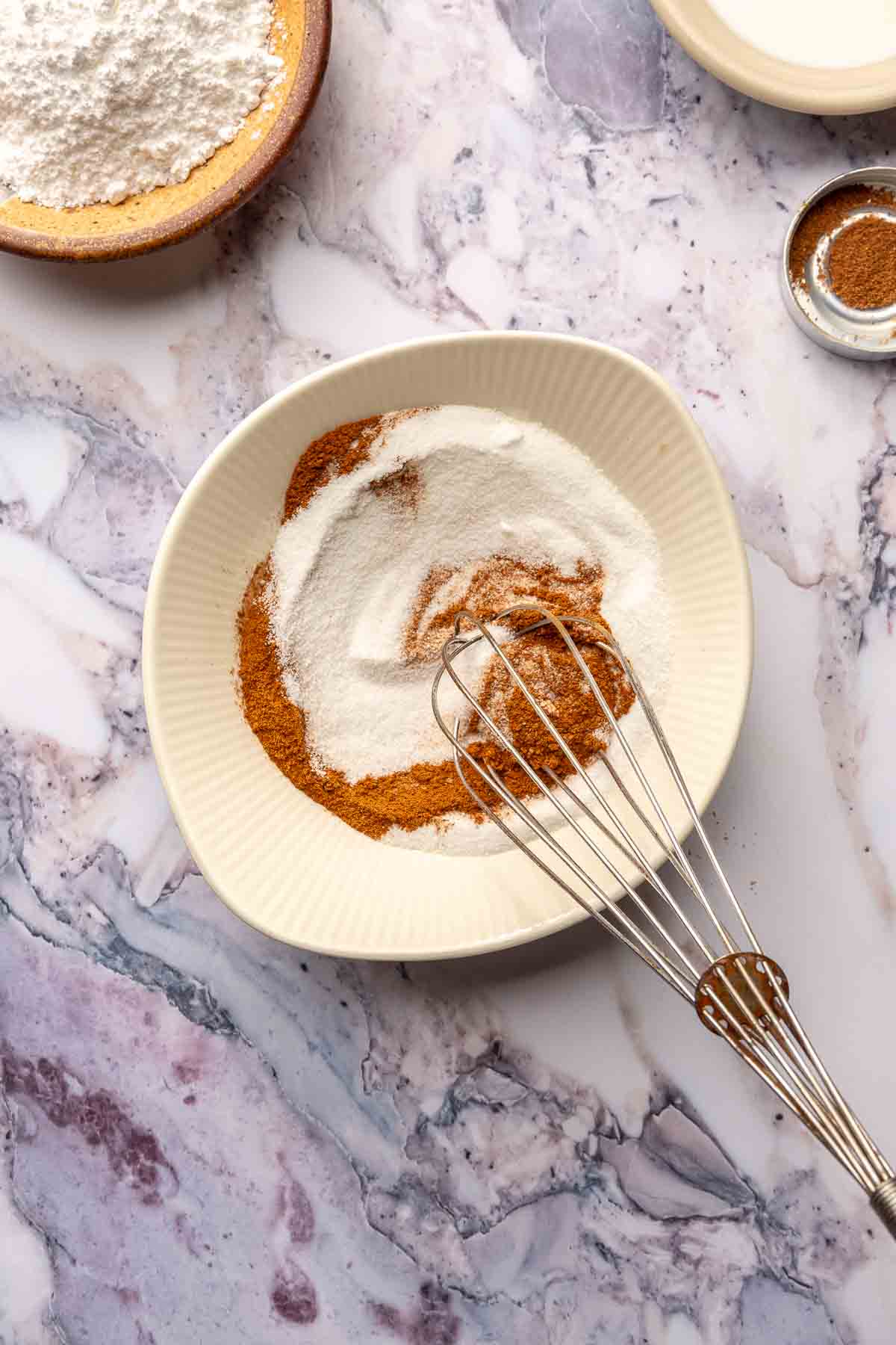 Whisking sugar with cinnamon in a small bowl.