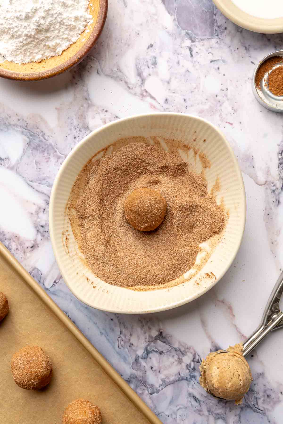 Rolling cookie dough ball in cinnamon and sugar.