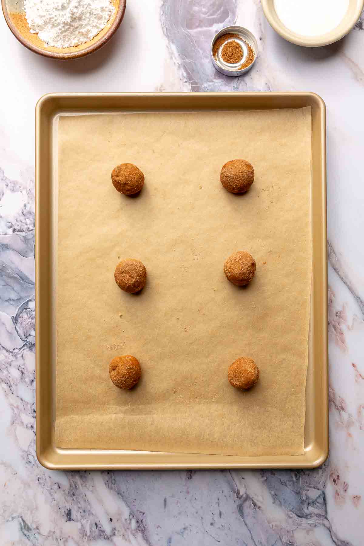 Cookie dough balls on a baking sheet lined with parchment paper.