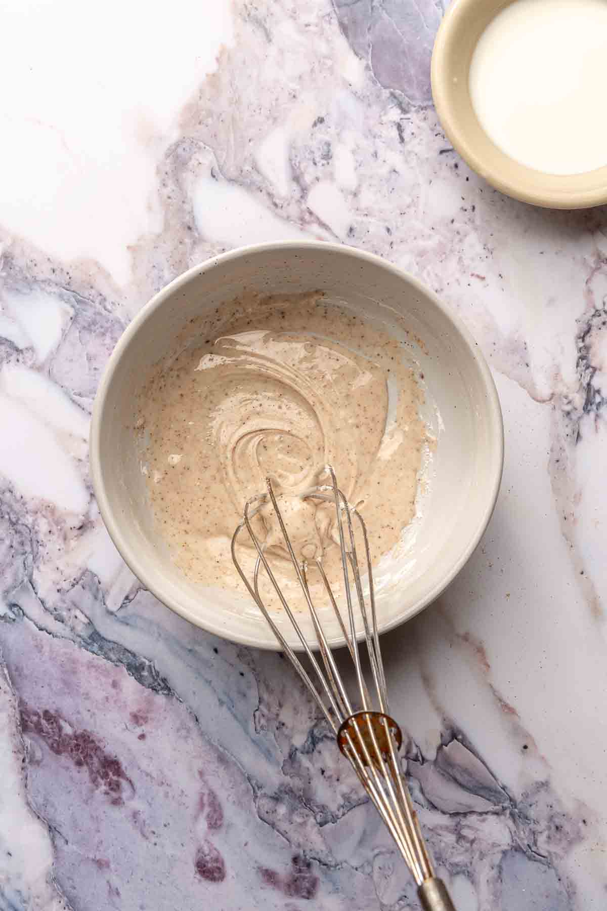 Whisking together nutmeg, powdered sugar and milk for icing.