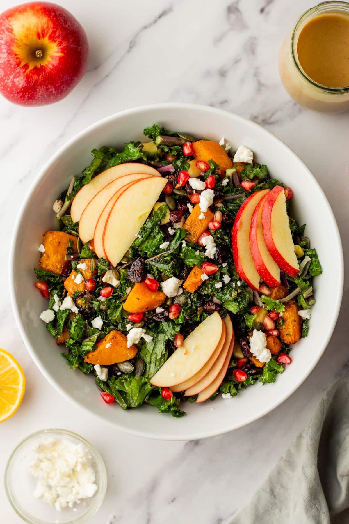 Butternut squash salad made with kale and topped with goat cheese and apple slices.