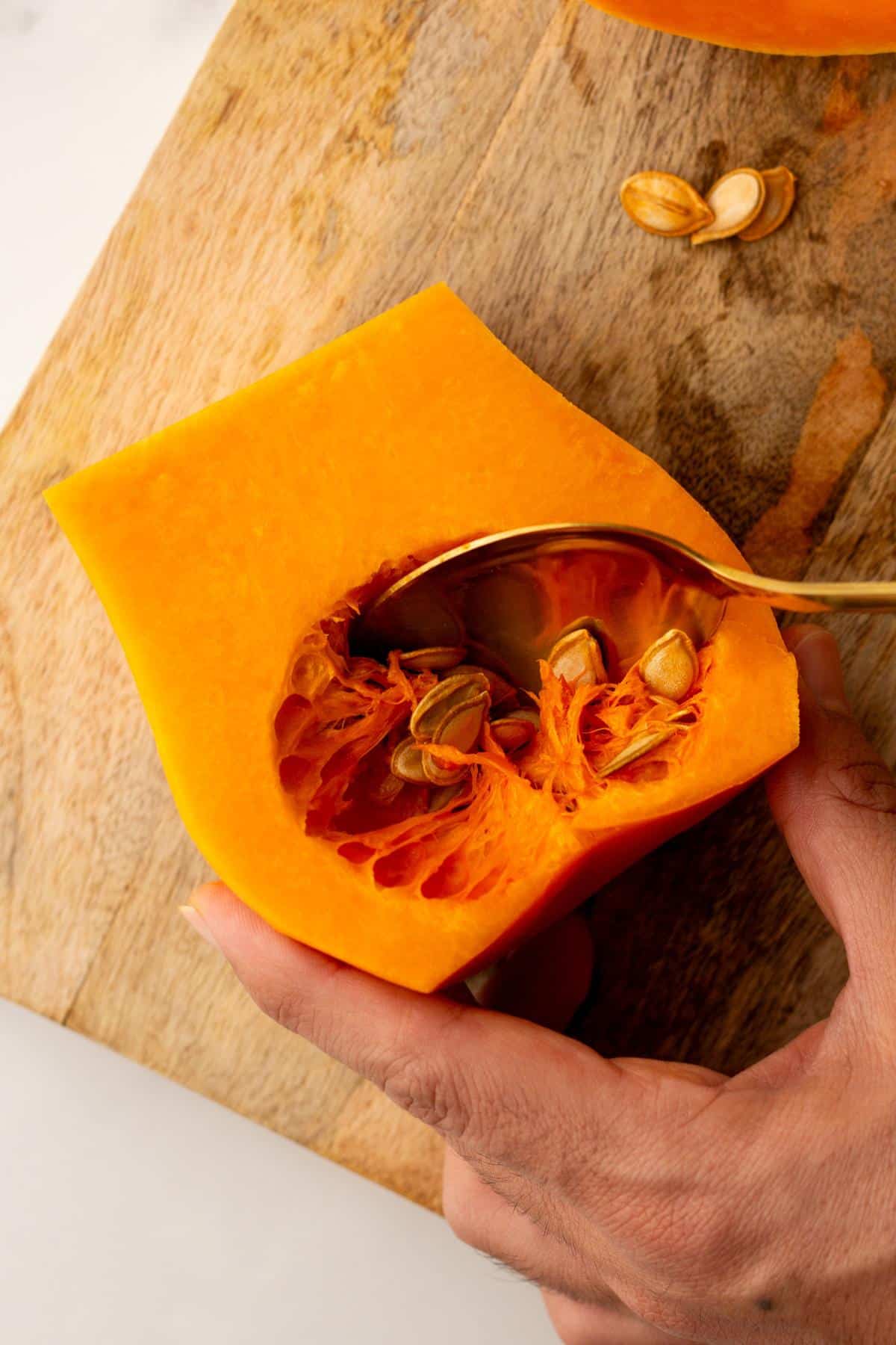 Scooping seeds out of a butternut squash.