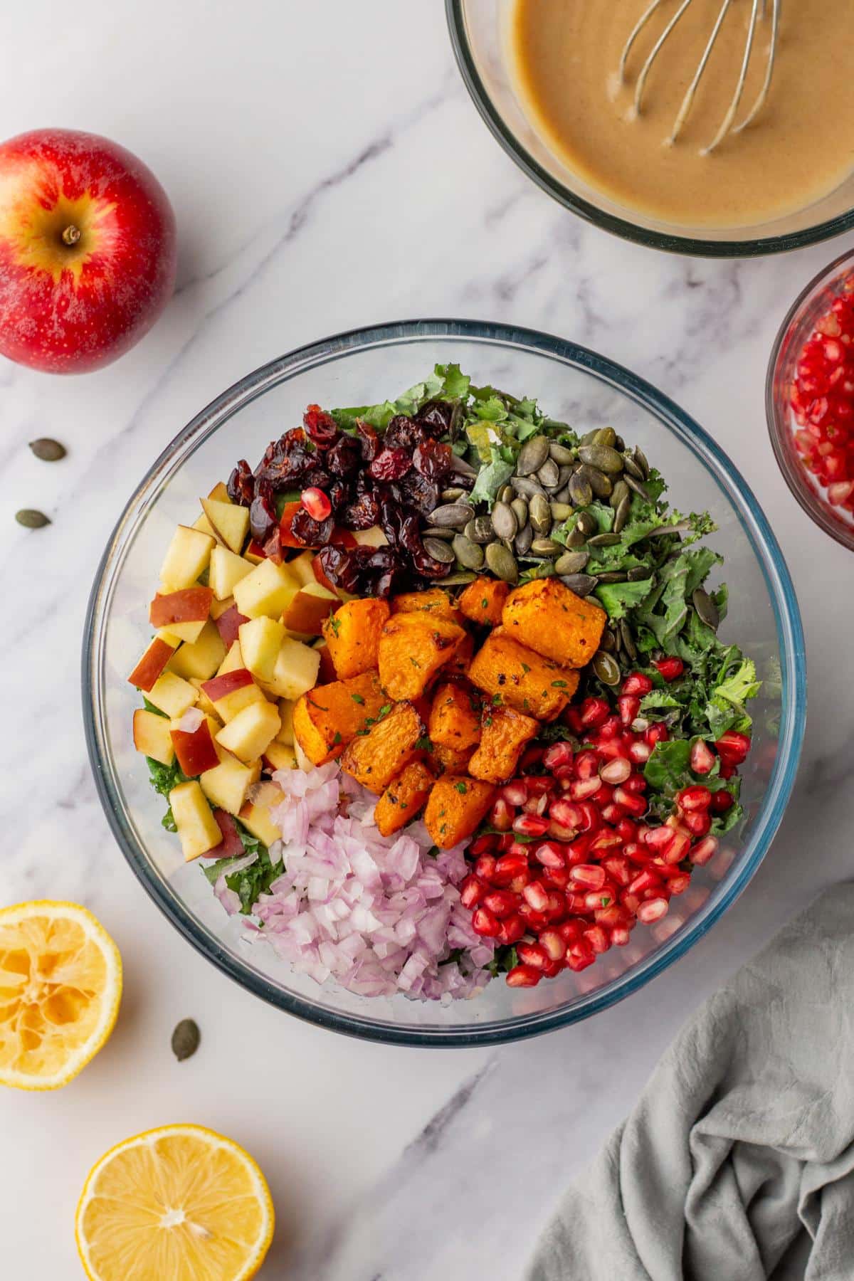 A large bowl with kale, butternut squash, red onion and pomegranate seeds.