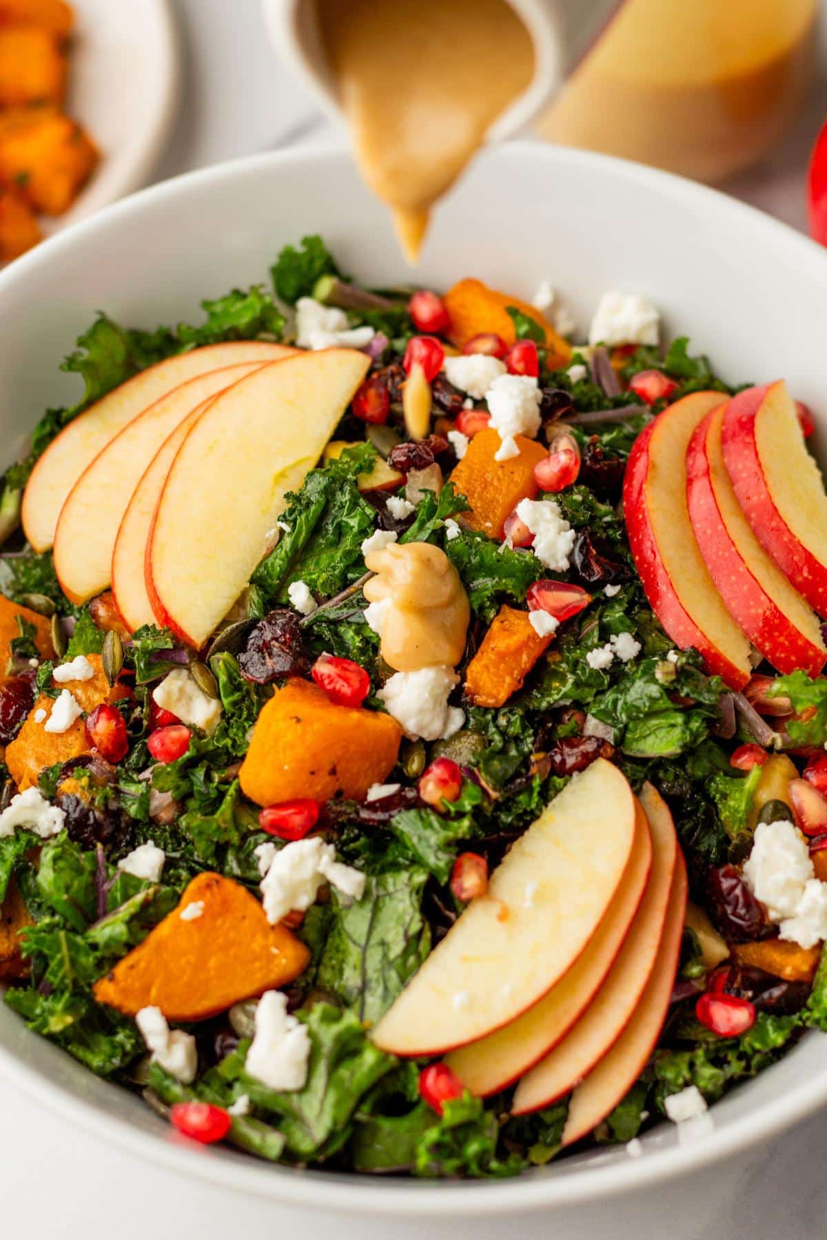 Pouring dressing over a butternut squash salad.